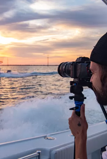 man taking photos of boat in the sunset